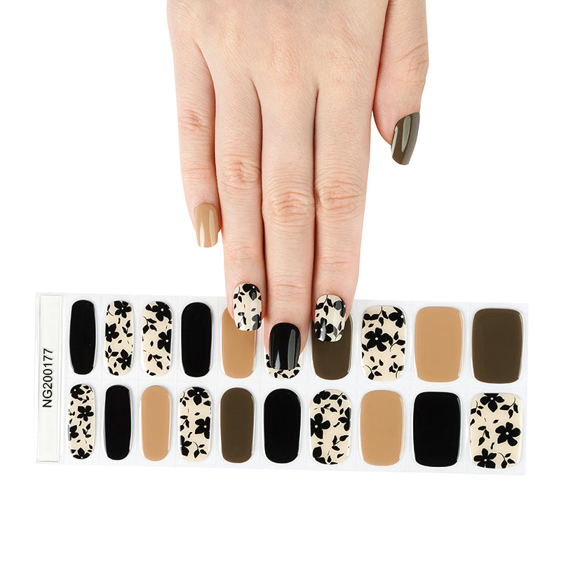 Hand holding a set of Set of 20 semi-cured gels nail wraps with a chic mix of earthy autumn shades and bold black florals nail wraps.