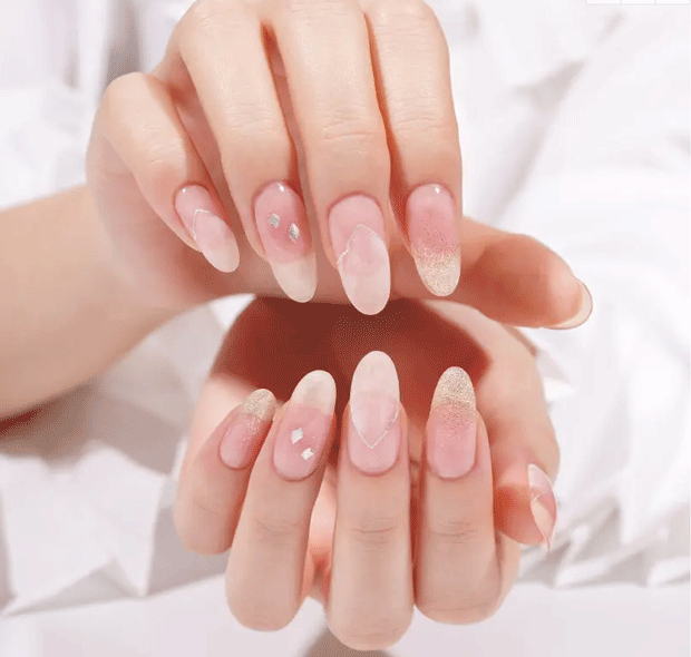 Close-up of hands with pink and gold glitter gel nail strips on a white background