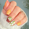 Hand with Easter-themed nail art stickers in green and yellow