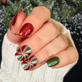 Hand with festive green and red swirl nail wraps in front of a Christmas-themed background