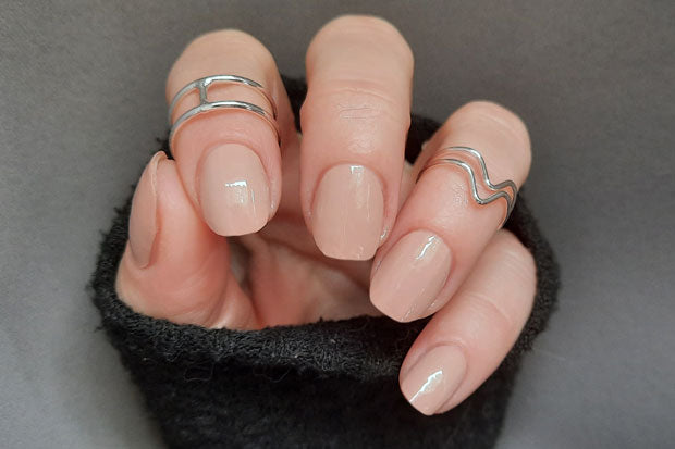 A set of nail wraps in a neutral beige shade, displayed on a hand showcasing a manicure.