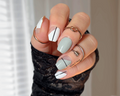 Hand with stylish white and grey nail wrap design with black lines.