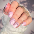 Close-up of a hand with pink nail polish wraps with chunky pink glitter on a blurred background