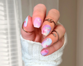 Hand with pastel nail art and multiple rings against a blurred background