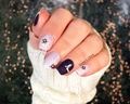 Hand with decorated snowflake nails in various shades of blue against a blurred background