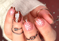 Nails with snowflake nail wrap and plaid designs against a blurred background.