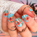 Nail wraps with floral design held against a blurred background