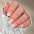 Hand wearing Peach Fizz peach ombré nail wraps with a white fade and delicate shimmer.