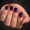 Sacred Craft black nail wraps with purple glitter gradients on short nails, framed by a charcoal sweater against a dark background.