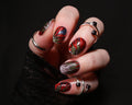 Hand with red and green nail polish strips on a black background