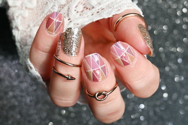 Hand showing geometric nail wrap design with glittery accents.