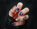 Hand with colorful nail art and multiple rings on a dark background