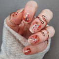 A set of nail wraps with a Thanksgiving-themed design, featuring cute turkeys in various colors, applied to a person's nails.