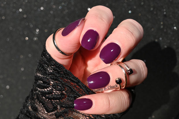 Nails showing very dark purple nail wraps under natural sunlight.