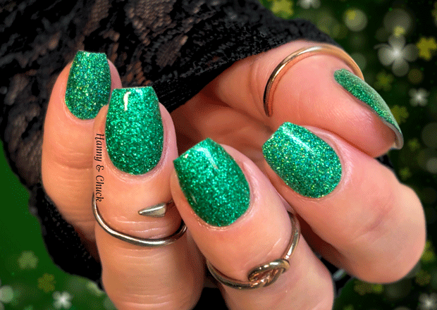 Close-up of a hand with green glittery nail wraps against a blurred green background