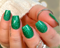 Close-up of a hand with green glittery nail wraps on a blurred natural background