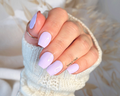 Hand with light purple nail wraps wearing a white knit sleeve.