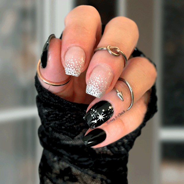 Hand with black and white glittery nail wrap design wearing a black textured sleeve.
