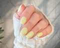 Hand with light yellow nail stickers on a neutral background