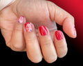 Close-up of a hand with red and pink nail wraps on a red background