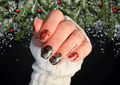 Hand with festive nail art stickers against a snowy background