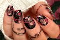 Hand with floral and skull nail wraps wearing multiple rings on a blurred background