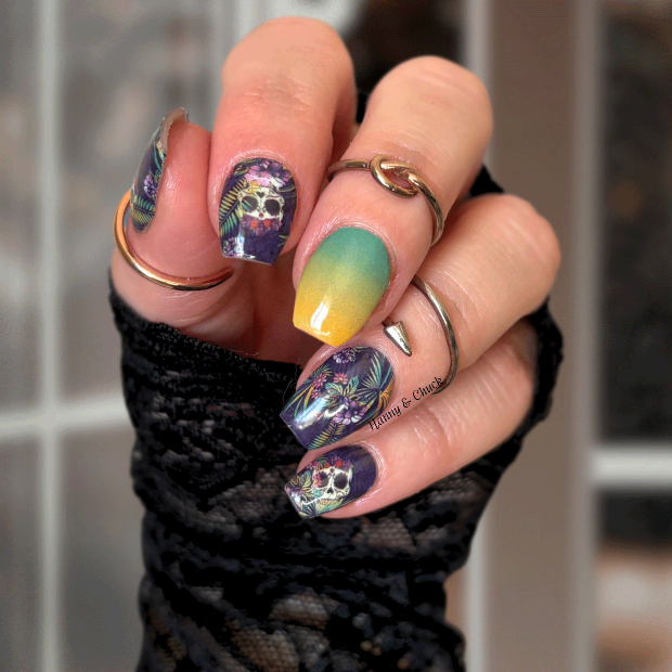 Close-up of a hand with colorful nail art and multiple rings against a blurred background