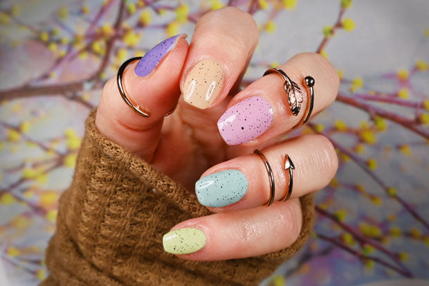 A hand wearing pastel speckled nail wraps