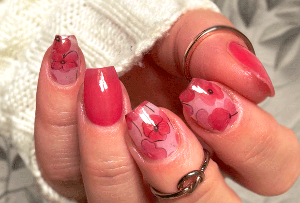 Hand with red poppy nail wrap design  on a blurred background