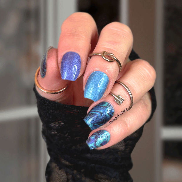Hand with blue nail polish wraps and multiple rings against a blurred background