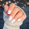 Hand with white nail polish wraps against a blurred starry night sky background