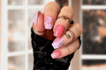 Hand with coral, lavender and pink floral nail wraps wearing black sleeve