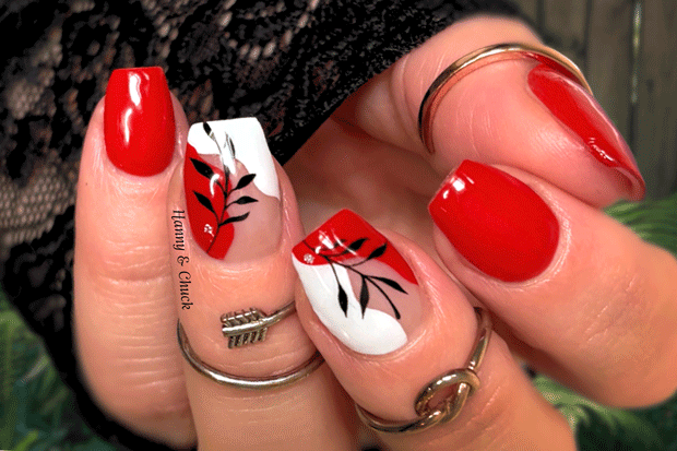Close-up of a hand with red, white, and black nail art on a blurred background