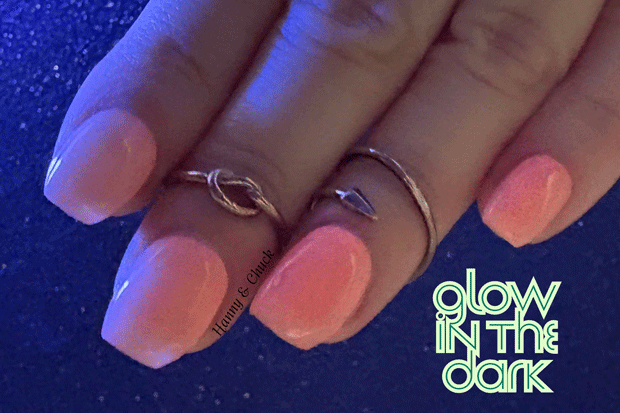 Hand with pink nail polish strips and rings on a dark background with 'glow in the dark' text.