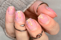 Close-up of a hand with pink glitter nail wraps and glittery accents.