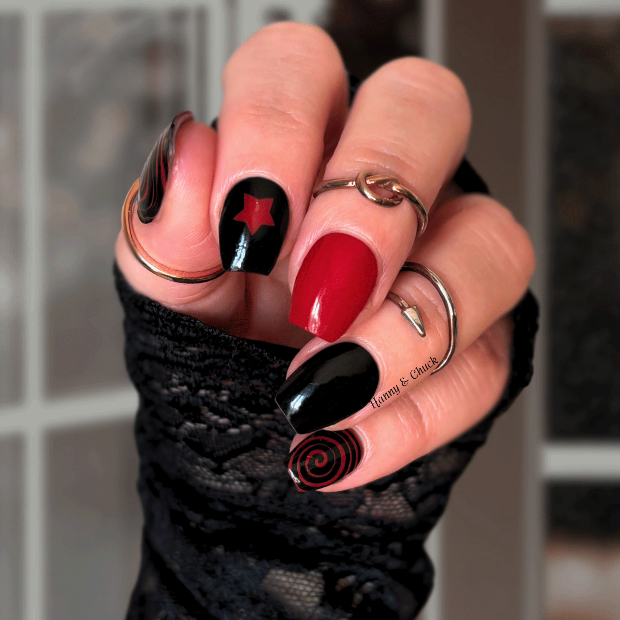 Hand with black and red nail polish wraps wearing a black glove against a blurred background