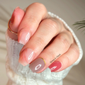 Close-up of a hand with pink, brown and gold nail polish wraps wearing a white sleeve.
