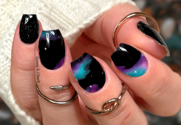 Close-up of a hand with black and purple gradient nail strips.