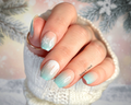 Hand with light blue and nude snowflake  nail polish against a blurred background