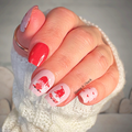 Hand with red and pink gnome themed nail polish strips and heart designs, wearing a white knitted sleeve.