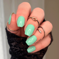 Hand with aqua green nail wraps and black lace sleeve against a neutral background