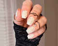 Hand with beige nail wraps and star and gold moon designs, wearing black fingerless gloves.