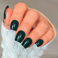 Black Forest dark green nail wraps on short square nails with a glossy finish and white knit sweater.