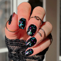 Hand with black glittery nail polish wraps wearing a textured sleeve.