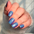 Hand with blue and purple glittery nail wraps.