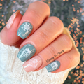 Hand with festive nail art against a blurred background with lights
