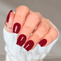 hand with dark red nail wraps applied.
