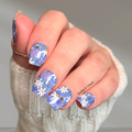 Hand with floral and bee nail design on a neutral background