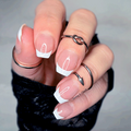 Close-up of a hand with french manicure nail strips and multiple rings on a neutral background