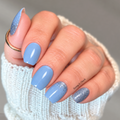 Frozen Over nail wraps on a hand, featuring cornflower blue nails, blue glitter gradients at the cuticles and a full blue glitter pinky.